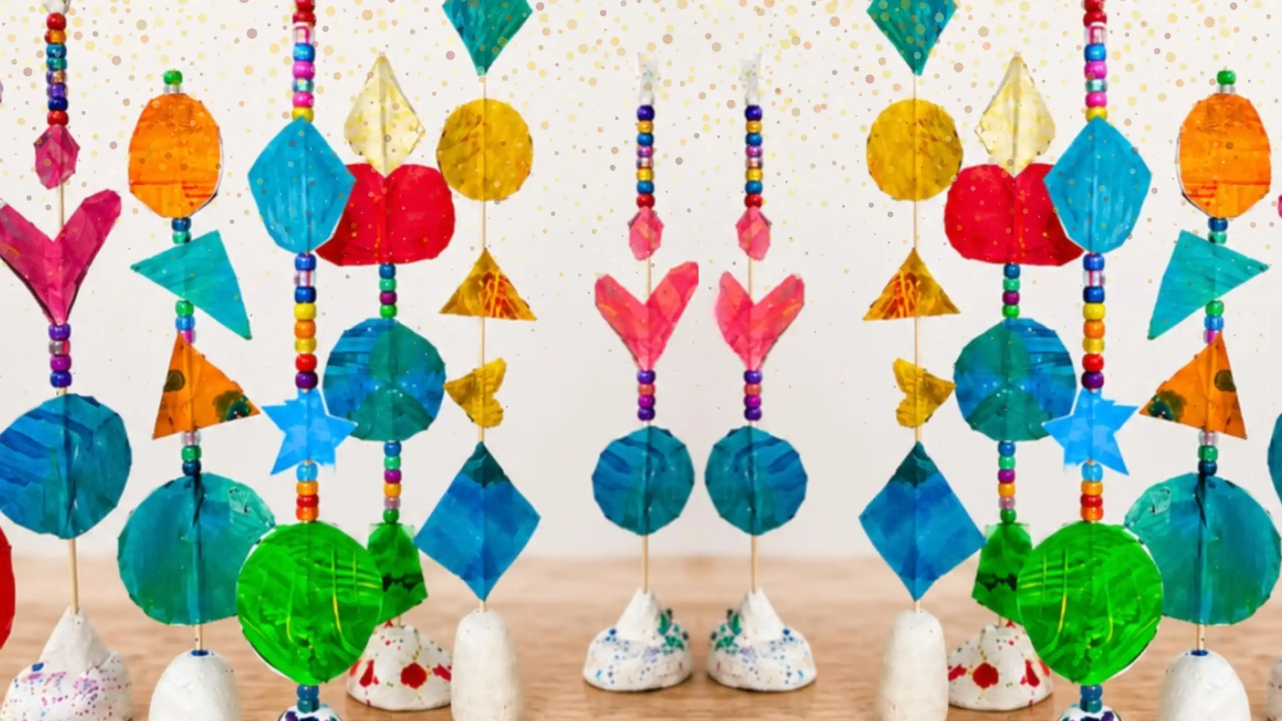 Colourful sculptures made from painted shapes, beads and skewers on white clay bases.